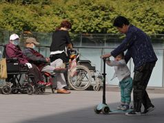 Женщина играет с ребенком рядом с пожилыми людьми в инвалидных колясках в Пекине. Фото: Andy Wong / AP